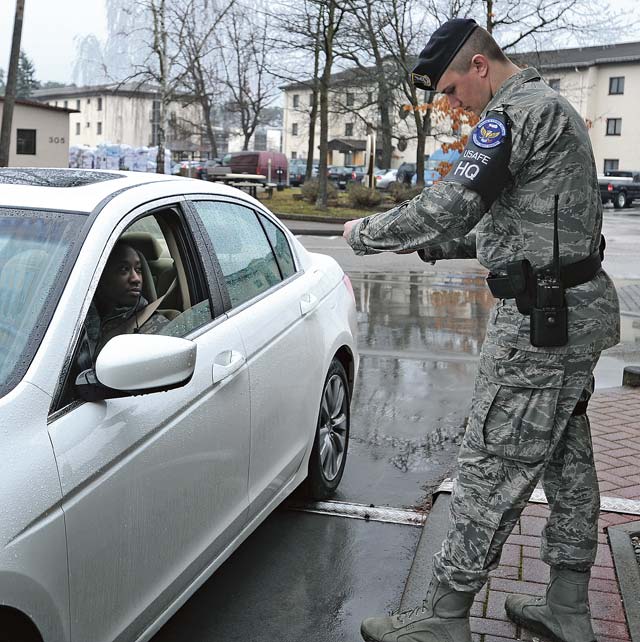 Airman 1st Class Christian Kampe, 86th Security Forces Squadron defender, hands an Airman her identification card after checking it at an entry point Feb. 5 on Ramstein. Kampe is one of many first-term Airmen who are responsible for ensuring base operations run smoothly.