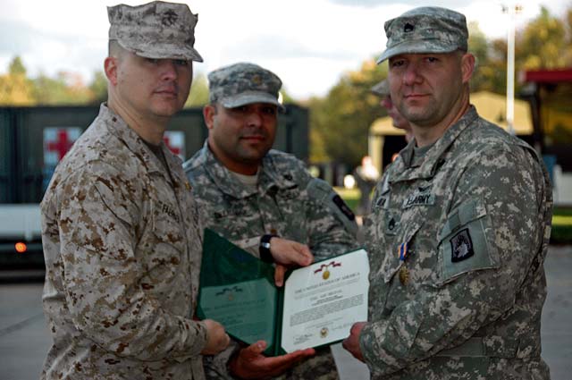 Lt. Col. Pete Faerber (left) and Maj. Jesse Delgado (center) present  Staff Sgt. Tim Mika with the Air Medal Oct. 30 at the Landstuhl Army Heliport.
