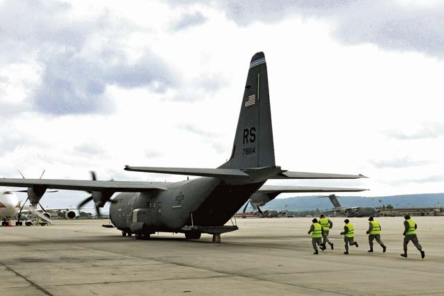 Airmen from the 721st Aerial Port Squadron participate in an engine-running offload. APS Airmen moved cargo on and off a C-130 Hercules as the engines were running. This cargo offload procedure significantly reduces the time an aircraft has to be on the ground before takeoff.