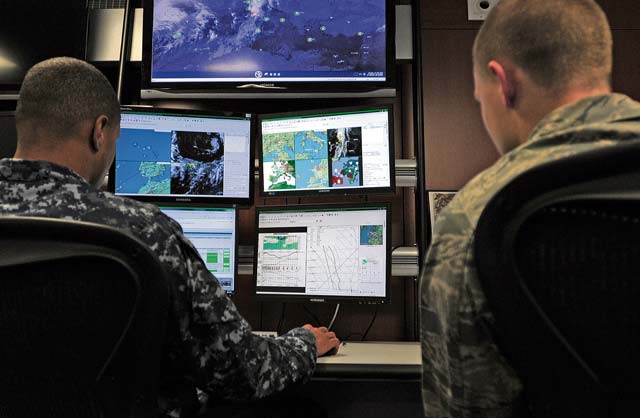 Photo by Airman 1st Class Holly MansfieldAerographers Mate 1st Class Rhyan Winbush and 2nd Lt. Brian Popick, 21st Operational Weather Squadron weather forecasters, observe maps of different areas to predict the weather before participating in an evacuation exercise Oct. 24 at Kapaun Air Station. The 21st OWS conducts inspections every quarter to prepare operations at an alternate location if the primary location can’t be accessed.