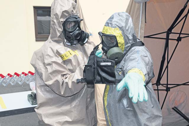 Sgt. Bajram Peci (left), leader decontamination station, 1st Platoon, HAZMAT Company, Civil Protection Regiment, Kosovo Security Force, removes a chemical protection suit from Staff Sgt. Wendell Reeder, survey team chief, 773rd Civil Support Team, 7th Civil Support Command, during a Defense Threat Reduction Agency-sponsored preparedness partnership exercise Aug. 20 on Panzer Kaserne.