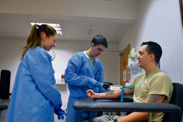 Senior Airman Josef Ansorge (center), 86th Medical Support Squadron laboratory technician, demonstrates how to draw blood from Staff Sgt. Dean Hall, 521st Air Mobility Operations Wing, to Ramstein High School student Brittany Overton Jan. 22 on Ramstein.