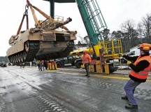 German railway loadmasters with the Theater Logistics Support Center-Europe control an Abrams main battle tank as it is crane loaded onto a rail car at the TLSC-E railhead March 19.