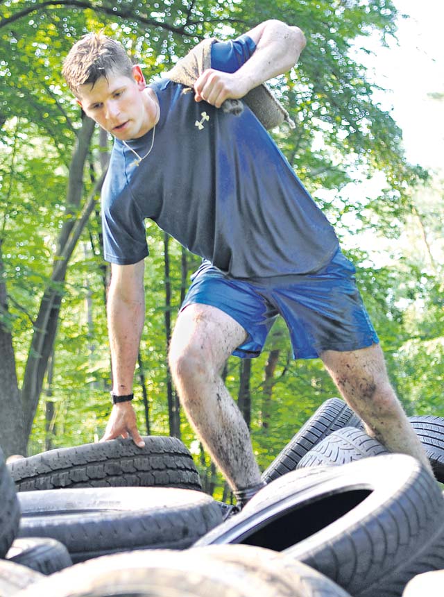 A Mudless Mudder participant climbs over a hill of tires. Each team had to carry a sandbag throughout the course without spilling it.