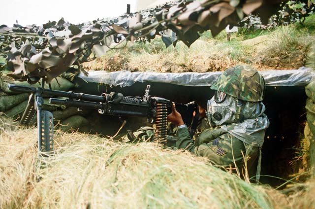 A U.S. Air Forces in Europe Airman wears head protection gear against chemical weapons while manning an M-60 machine gun during Exercise Reforger ’81 at Ramstein.