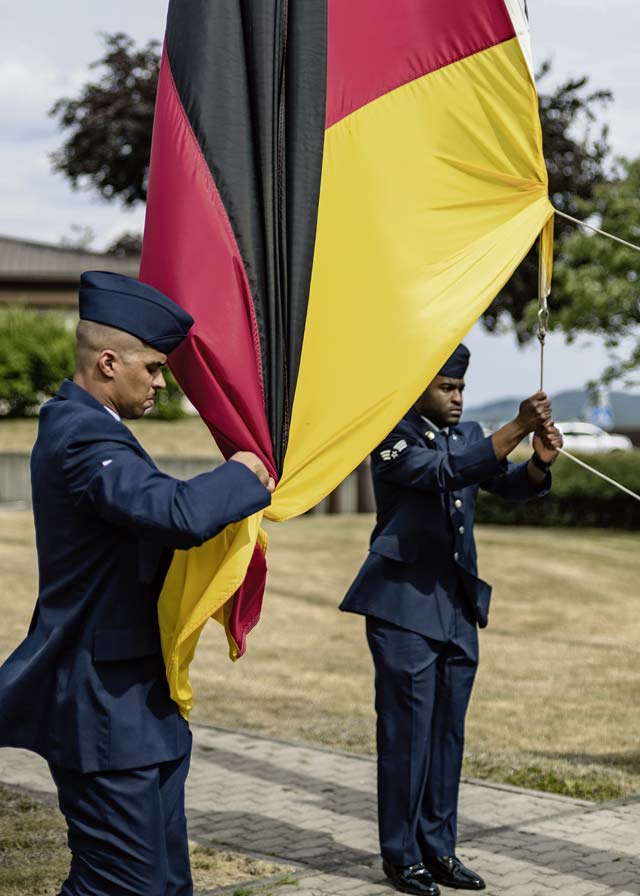 Two 86th Aircraft Maintenance Squadron Airmen secure the German flag during a retreat ceremony.