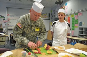 U.S. Army CW2 Bill Michitsch, 10th Army Air and Missile Defense Command G-4 food service technical adviser, shows students at Ramstein Middle School how to attractively garnish fruits and vegetables May 17. The students were part of the Advancement via Individual Determination college preparatory program, which showcases life skills needed to succeed in a variety of careers.