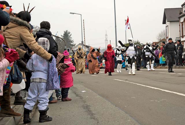 Members of the crowd look on as participants walk down the street as part of the Fasching parade Tuesday in Ramstein-Miesenbach.