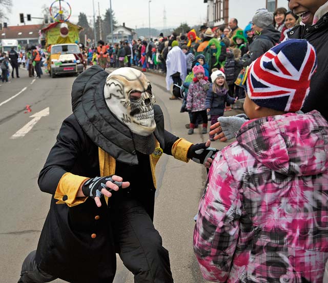 A parade participant interacts with a crowd member during the Fasching parade in Ramstein-Miesenbach.