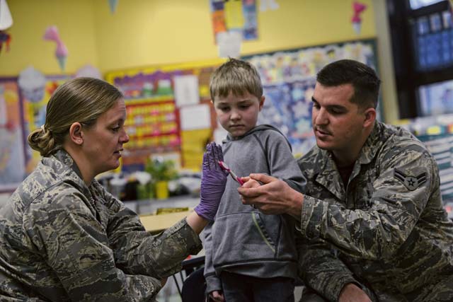 Maj. Audra Myers and Airman 1st Class Drake Futch, 86th Dental Squadron dentist and dental assistant, teach a Ramstein Elementary School student how to floss and brush their teeth during a dental hygiene presentation on Ramstein.