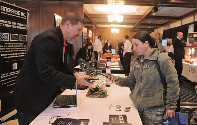 Technological exhibitor Darryl Stewart (left) shows the features of the SRX 2200 Land Mobile Radio to Chief Master Sgt. Ruth Urbina, 435th Air and Space Communications Group.