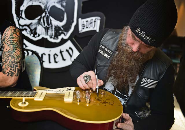 Zakk Wylde, lead vocalist, rhythm guitarist and pianist for the Black Label Society, signs a guitar for an Airman. Wylde, a former guitarist for Ozzy Osbourne, and the band put on a free concert for Team Ramstein with the help of the USO.