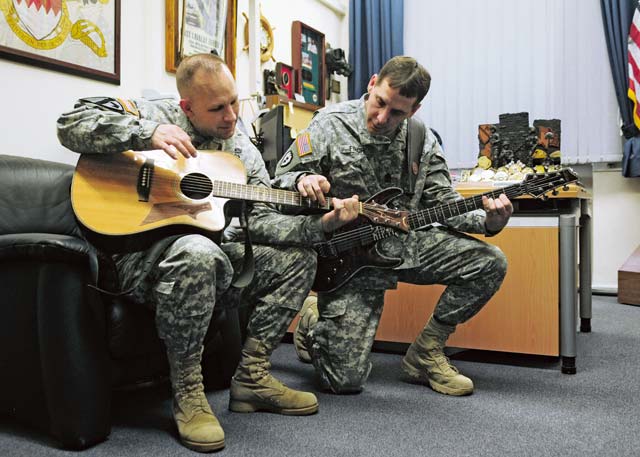 Photo by Brandon BeachSgt. Maj. Shawn M. Firch, 21st Theater Sustainment Command secretary general staff sergeant major, teaches Command Sgt. Maj. Rodney J. Rhoades, 21st TSC senior enlisted leader, how to play the guitar during some down time Feb. 22 on Panzer Kaserne.