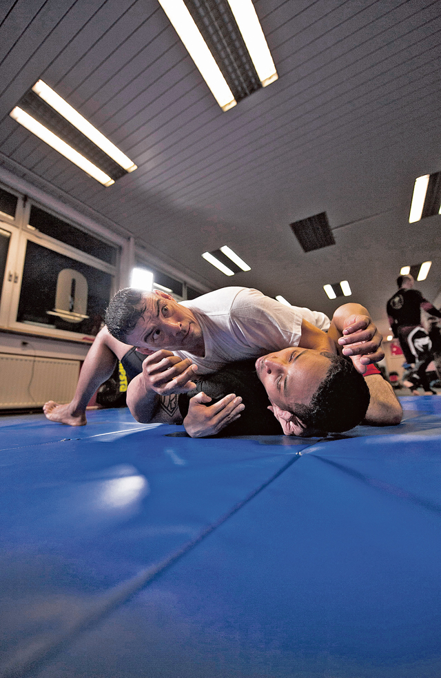 Joe Stojak (top) and U.S. Army Spc. Forrest Powell demonstrate a mixed martial arts technique during a training session.  Stojak, a U.S. civilian contractor and Army veteran, volunteers his time to train U.S. military members and German nationals in MMA.