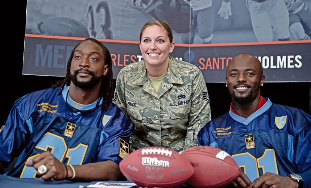 Charles Tillman, an NFL cornerback who was the Walter Payton Man of the Year in 2013, and Santonio Holmes Jr, an NFL wide receiver and MVP of Super Bowl XLIII, pose for a photo with Staff Sgt. Theresa Buck, 72st Aircraft Maintenance Squadron, unit security manager, during the USO’s ProTour 2015, April 15 on Ramstein.