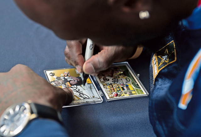 Santonio Holmes Jr, an NFL wide receiver and MVP of Super Bowl XLIII, signs a football card during the USO’s ProTour 2015. Holmes, along with Charles Tillman, an NFL cornerback who was Walter Payton Man of the Year in 2013, flew to Europe to visit with service members and with wounded, ill and injured military members at the Warrior Care Center at Landstuhl Regional Medical Center. 