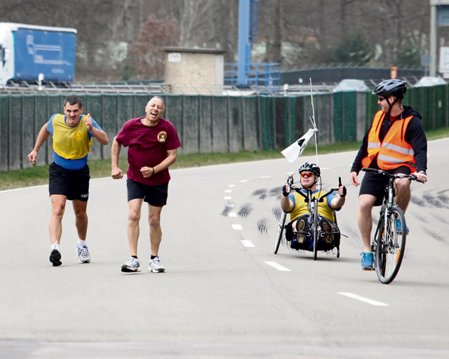 Courtesy photo Commander’s Cup Triathlon: Maj. Keithen (Wiesbaden) tries to catch Michael Barnett (BN Kaiserslautern) close to the finish line of the race/walk portion of the Commander’s Cup Triathlon competition April 17. On the hand crank bike, Master Sgt. Brock White (Wiesbaden) helps pace the walkers while Senior Airman Kevin Kelly watches for rule infractions.