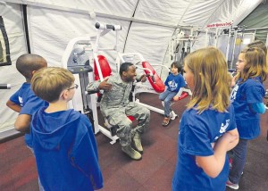 Staff Sgt. Terry Cooper, 435th Construction and Training Squadron services contingency instructor, teaches Ramstein Intermediate School students how to properly use fitness equipment. Ramstein units came together and gave RIS students the opportunity to deploy like their Airmen and Soldier parents. 