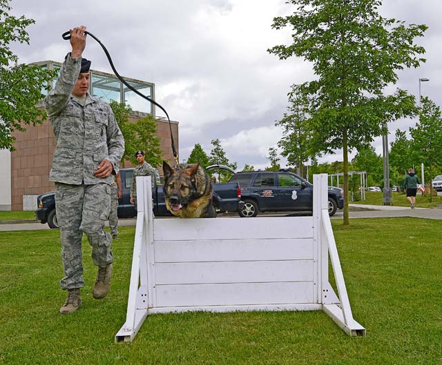 Staff Sgt. Chad Coe, 86th Security Forces Squadron Military Working Dog handler, leads Charone, 86th SFS MWD, over a hurdle as part of a MWD demonstration.