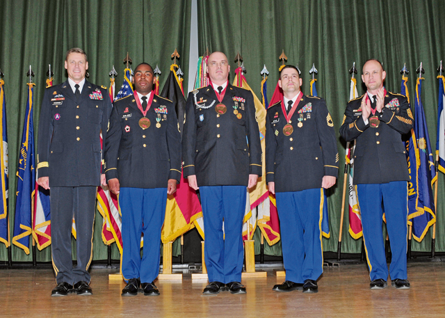 Newly inducted members of the Sergeant Morales Club stand with Maj. Gen. John R. O’Connor (left) and Command Sgt. Maj. Rodney J. Rhoades (right), the commanding general and the senior enlisted leader of the 21st Theater Sustainment Command respectively, during an induction ceremony May 19 on Smith Barracks. 