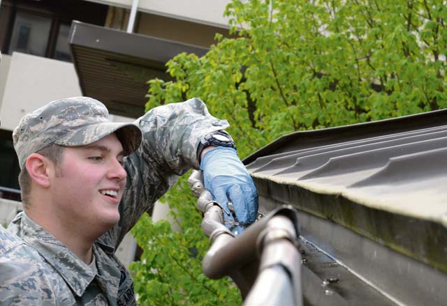 An Airman cleans out the gutter of a pavilion during Base Pride. Airmen living in the dormitories and base housing cleaned the buildings and the surrounding areas where they lived in order to keep the base clean.