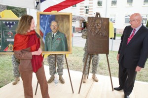 Photo by Rick Scavetta, U.S. Army Garrison Public Affairs Christa Dirgins and retired Gen. Gordon Sullivan unveil a shadowbox, painting and plaque dedicated to the late Brig. Gen. Richard Dirgins April 17 at Daenner Kaserne.