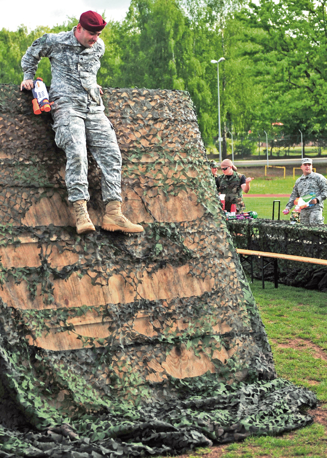 Army Sgt. Robert R. Kennedy, a parachute rigger with the 21st Theater Sustainment Command’s 5th Quartermaster Detachment, 39th Transportation Battalion, 16th Sustainment Brigade, climbs the wall of an obstacle course during the Joint Combat Dining-In.