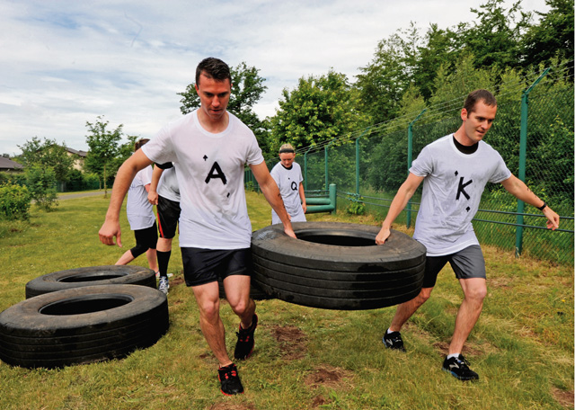 Members of team "Royal Flush" perform a tire carry during the Mudless Mudder event which gave members an opportunity to strengthen team-building skills.