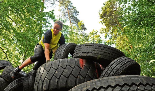 A member of team "Dorm Rangers" climbs a tire wall during the Mudless Mudder event.