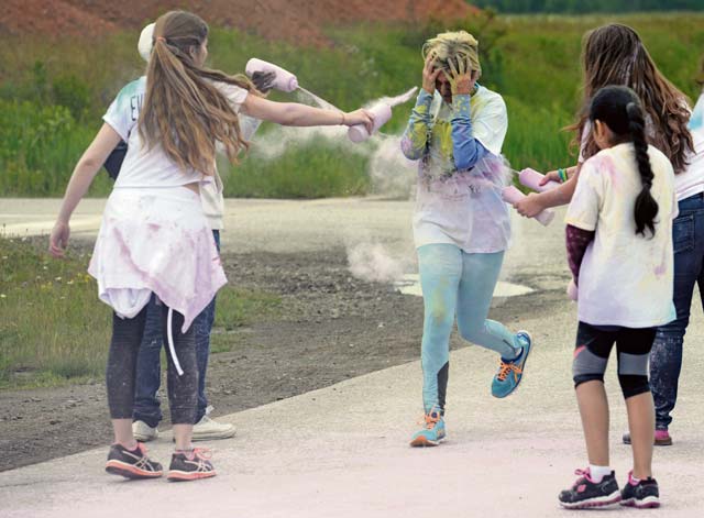 A participant in the Keystone 5K Color Run covers her face as she runs through a color station. 