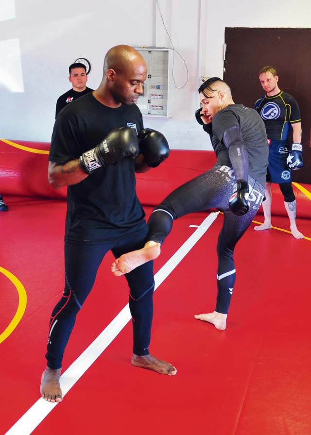 The Outlaw (right), demonstrates how to properly deliver a low kick on Sgt. 1st Class Ron Foster, a military police NCO assigned to the 21st Special Troops Battalion, 21st Theater Sustainment Command.
