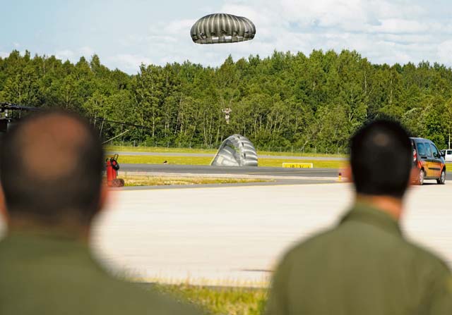 Pilots watch as U.S. Army members land during a combined jump day with the Latvian armed forces June 15 at Lielvarde.
