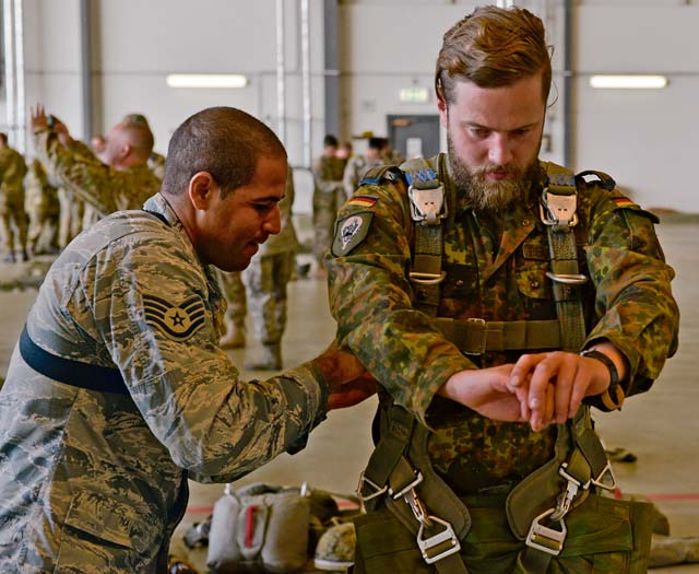 Photo by Airman 1st Class Lane T. Plummer Staff Sgt. Pedro Palmer, 435th Security Forces Squadron contingency response fire team leader, assists a German military member with his harness before loading onto a C-130J Super Hercules July 9 on Ramstein. The 435th Contingency Response Group invited nine allied nations to participate in International Jump Week to boost camaraderie and learn how to work together. 