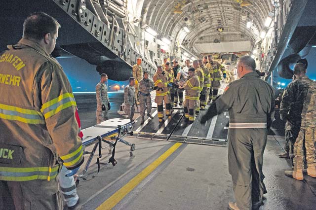 Firefighters from the 86th Civil Engineer Squadron KMC Fire Emergency Services and personnel from the 10th Aeromedical Evacuation Operations Team and 455th Critical Care Air Transport Team standby to assist in the transport of a patient during an aeromedical evacuation mission Aug. 9 on Ramstein. A C-17 Globemaster III transported the patient from Kabul, Afghanistan, to Ramstein.