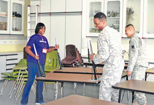 Sgt. Maj. Michael Ledesma (right) and Master Sgt. Addley Saimbert, both members of the Rheinland-Pfalz chapter of the Sergeant Morales Club, help Angela Hampton, a science and social studies teacher at Sembach Middle School, by moving boxes and furniture to her new classroom Aug. 26.