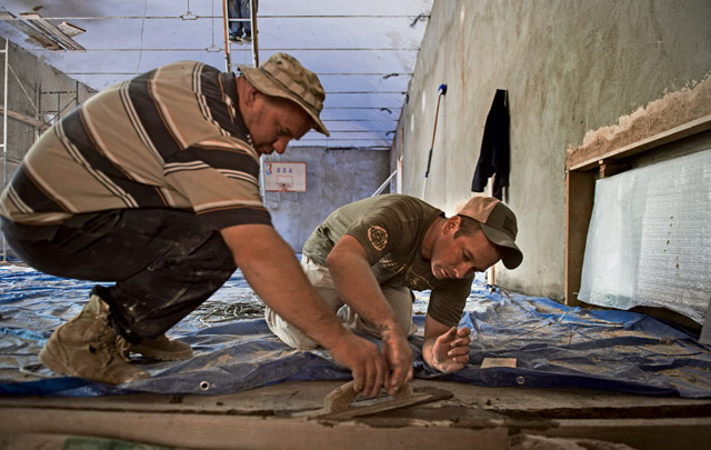 U.S. Air Force Staff Sgt. David Dengate, 435th Construction and Training Squadron pavement and equipment operator, works with a Georgian army engineer to help fill in concrete in the entrance to the gymnasium of Public School No. 4 Aug. 27 in Gori, Georgia. U.S. Air Force and Georgian army engineers worked long hours side by side for more than 30 days to complete the renovation of a dilapidated school.