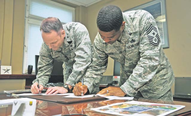 Brig. Gen. Jon T. Thomas, 86th Airlift Wing commander, and Chief Master Sgt. Phillip Easton, 86th AW command chief, sign pledge forms in support of the Combined Federal Campaign-Overseas Oct. 22 on Ramstein. The CFC-O allows U.S. military members and U.S. government civilian employees to donate to the charity of their choice, with more than 2,600 charities available to choose from.