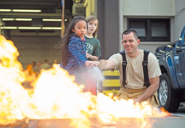 Master Sgt. Mark Goenen, 86th Civil Engineer Squadron KMC Fire Emergency Services, shows children how to properly use a fire extinguisher Oct. 8 on Ramstein. As part of Fire Prevention Week, families visited Fire Station 1 to learn about fire safety including home-fire safety issues, fire extinguisher training and holiday safety tips.