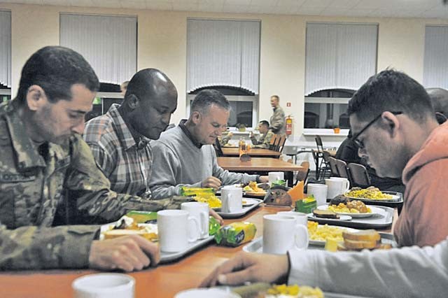 Maj. Brian Smith, 21st Theater Sustainment Command, 16th Sustainment Brigade chaplain, and Capt. Taiwo Arowosegbe, 39th Transportation Battalion, 16th SB chaplain, say grace before dinner with Soldiers Oct. 13 at Adazi Military Base in Latvia. The chaplains met with Soldiers, attended to their spiritual needs and provided religious counseling as necessary during their visit to Atlantic Resolve-North hubs in the Baltics. The tour also included stops in Poland, Lithuania and Estonia.