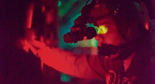 A C-130J Super Hercules pilot looks out the window of a C-130J Super Hercules  Oct. 30 above Powidz Air Base, Poland. Loadmasters must train at night to familiarize themselves with the aircraft in low-light situations.