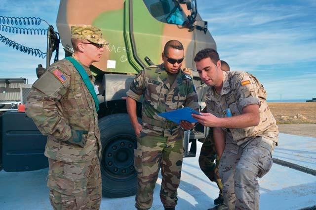 Photos by Sgt. 1st Class Michael O'Brien U.S. Army Sgt. Daryl Perez (left), French Petroleum, Oil and Lubrication Cpl. John Parau (center) and Spanish Air Force Pvt. Alejandro Sanudo, all members of Trident Juncture 2015's modular combined petroleum unit, coordinate exercise logistics Oct. 8 in Zaragoza, Spain. The MCPU fueled vehicles from nearly all of the 35 participating countries during the exercise.