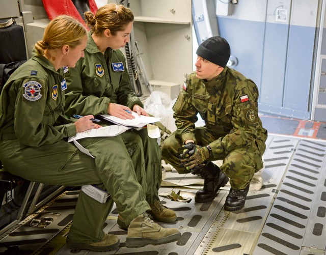 Polish air force 2nd Lt. Andrzej Nartonowicz, aeromedical evacuation doctor, listens to two 86th Aeromedical Evacuation Squadron Airmen as they prepare for a mock mission Dec. 3 on Ramstein. The 86th AES and other aeromedical evacuation specialists on Ramstein showcased procedures and tactics used to save lives for the developing Polish aeromedical evacuation mission.