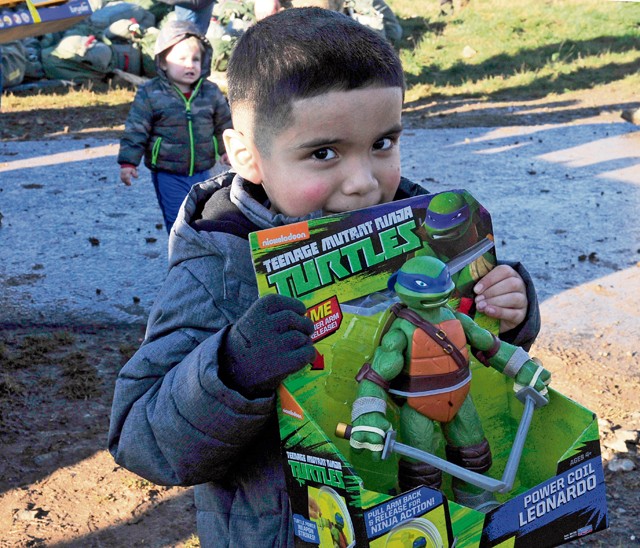Photo by Airman 1st Class Larissa Greatwood Julian Obregon, son of Tech. Sgt. Jose Obregon, 435th Contingency Response Group independent duty medical technician, shows off his toy from Santa Claus during the International Jump Week Toy Drop Dec. 7 at Alzey Drop Zone, Germany.