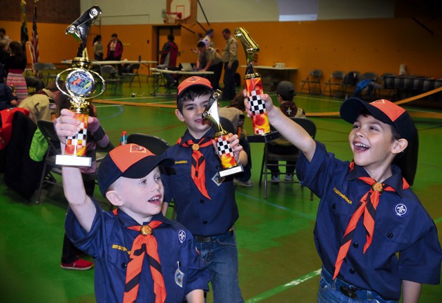 Tiger Cubs Kade Dressing, age 6 (left), Mason McMillan, age 7 (center), and Evan Zawojski,  age 7, celebrate their triumphs in the aftermath of the Pack 69 Pinewood Derby held Jan. 23 at Vogelweh Elementary School. Over 30 cars competed during the annual Scout racing extravaganza. Siblings, parents and adult volunteers as well as Scouts designed, cut and decorated wooden cars for the competition.