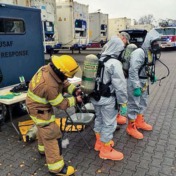 Courtesy photo Firefighters from the 86th Civil Engineering Squadron suit up in hazmat suits as they prepare to quell a chemical line rupture  Nov. 17, 2015, on Ramstein. The rupture spewed hazardous chemicals within a cold storage facility containing Defense Commissary Agency food items.