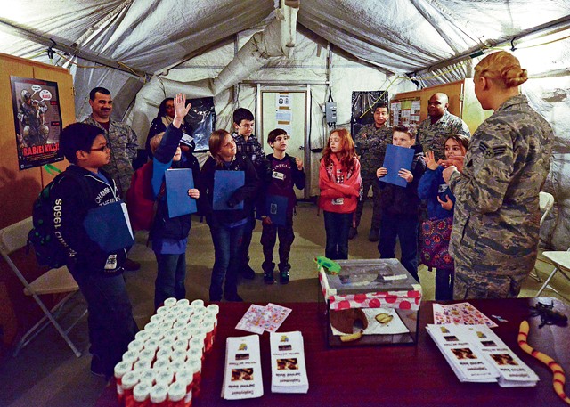 Photo by Tech. Sgt. Daylena Ricks Senior Airman Danielle Marsh, 86th Aerospace Medical Squadron public health technician, issues “medication” as well as “dosage instructions” during a mock pre-deployment line held on the 435th Air Ground and Operations Wing’s 435th Construction and Training Squadron’s silver flag compound March 27, 2015, on Ramstein. Ramstein units came together and gave Ramstein Intermediate School students the opportunity to deploy like their Airmen and Soldier parents.