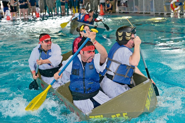Photo by Airman 1st Class Lane Plummer  Participants from the 786th Force Support Squadron paddle past other teams during the “Battle of the Battleships” competition May 15, 2015, on Ramstein. The competition began with boat races, where teams were tasked to paddle their custom-built boats from one end of the pool to the other as quickly as possible.