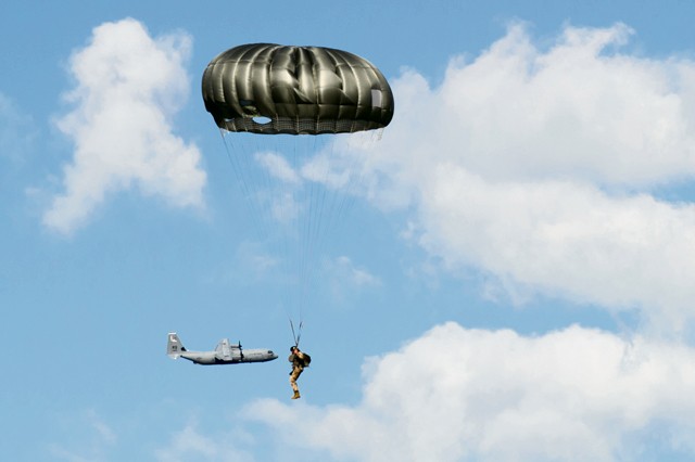 Photo by Staff Sgt. Armando Schwier-Morales A Ramstein C-130J Super Hercules passes behind a Latvian military member during a combined jump day June 15, 2015, at Lielvarde Air Base, Latvia. More than 70 U.S. Air Force, U.S. Army and Latvian service members participated in a jump day to strengthen the bonds of allies and learn from each other during exercise Saber Strike 15. The exercise involved more than 6,000 service members from 14 nations participating all throughout Estonia, Latvia, Lithuania and Poland to learn from each other and promote stability in the region.
