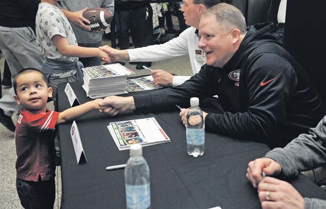Chip Kelly, San Francisco 49ers head coach, shakes hands with a young fan during a meet-and-greet for the 2016 Coaches Tour Feb. 14 on Ramstein. Fans had the opportunity to meet, talk with and get autographs from four coaches from both collegiate and professional leagues. 