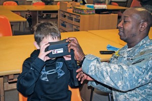 Photo by Jennifer OdellMaster Sgt. DaJuan Lowery, Headquarters and Headquarters Company, 30th Medical Brigade, assists Derrick Johnson, a Sembach Elementary School student, enter virtual reality. 